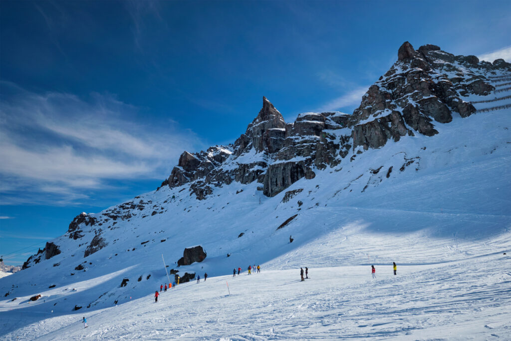View of a ski resort piste with people skiing in Dolomites in Italy. Ski area Arabba. Arabba, Italy