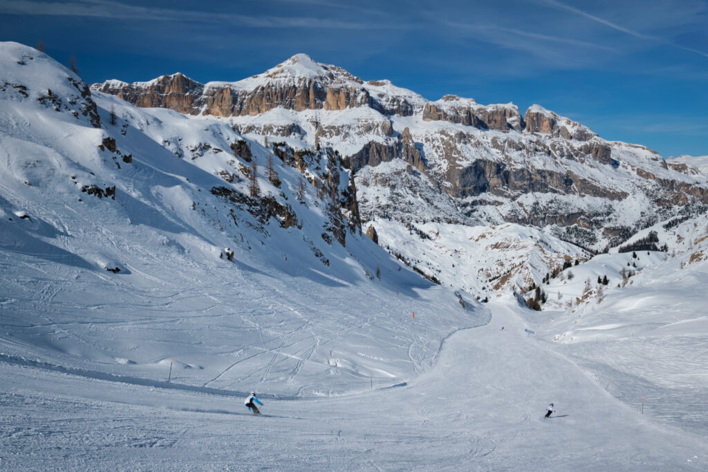 View of a ski resort piste with people skiing in Dolomites in Italy. Ski area Arabba. Arabba, Italy